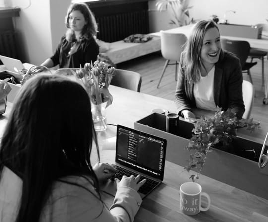 Photo of workers in office working on laptop