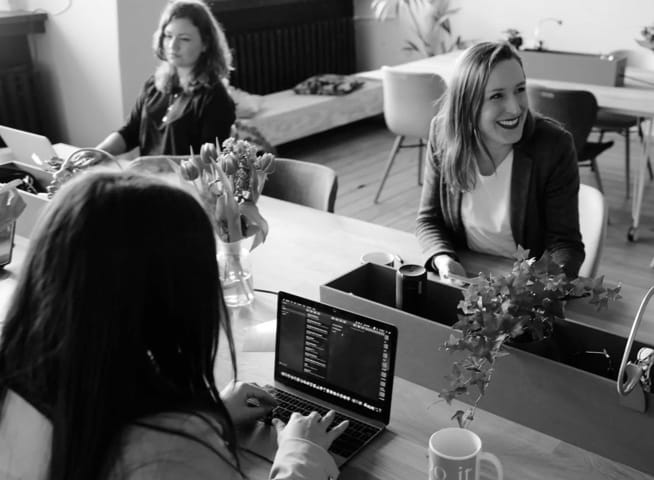 Photo of workers in office working on laptop